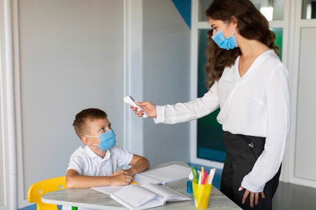 Teacher taking the temperature of a student