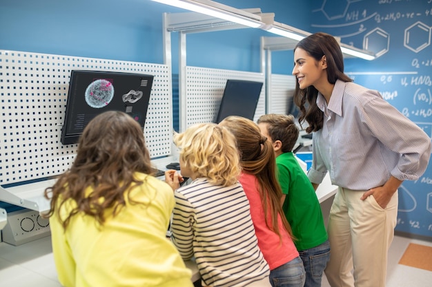 Free photo teacher with children looking at screen at lesson