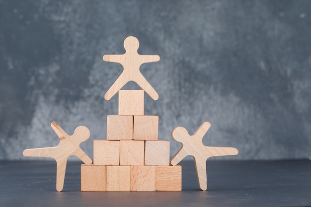 Team and business concept with wooden blocks like pyramid with wooden human figures.