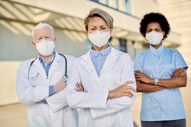 Free photo team of confident doctors wearing protective face masks due to coronavirus epidemic