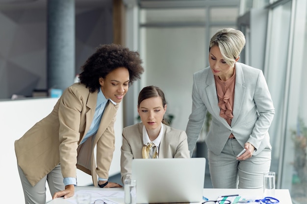 Team of female entrepreneurs cooperating while working on laptop during business meeting