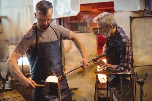 Team of glassblower forming and shaping a molten glass