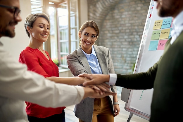 Free photo team of happy entrepreneurs gathering their hands in unity while celebrating success in the office