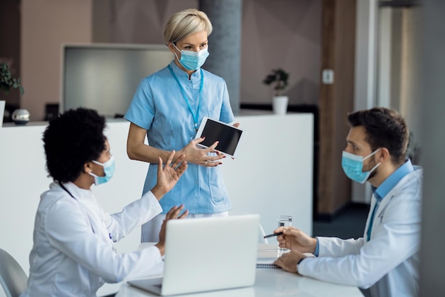 Free photo team of healthcare workers cooperating while using touchpad during a meeting at the clinic