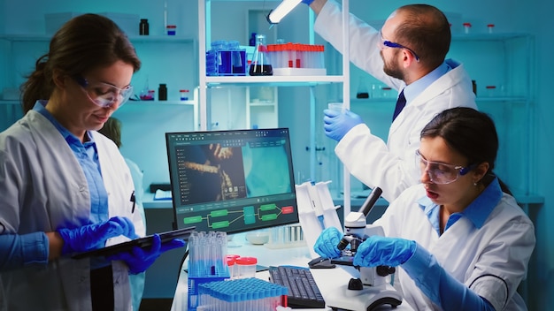 Free photo team of positive scientists working in chemistry equipped laboratory, nurse typing on tablet