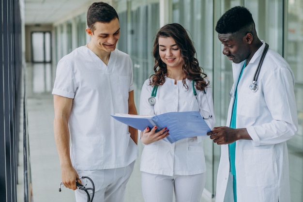 Free photo team of young specialist doctors reviewing documents in the corridor of the hospital