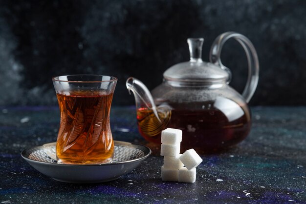 Teapot and glass of tea with sugar