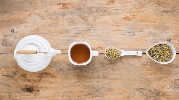 Free photo teapot; lemon tea and dried chinese chrysanthemum flowers arranged in a row on table