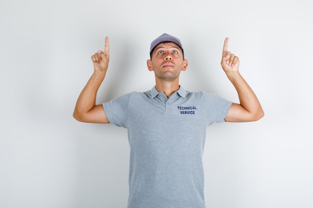 Free photo technical service man in grey t-shirt with cap pointing fingers up