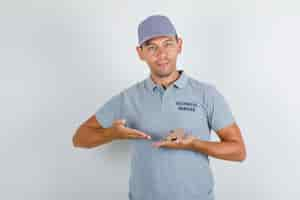 Free photo technical service man in grey t-shirt with cap showing wooden toy car