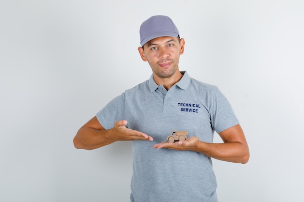 Free Photo technical service man in grey t-shirt with cap showing wooden toy car