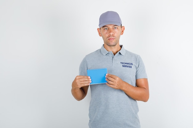 Free Photo technical service man holding mini notebook in grey t-shirt with cap