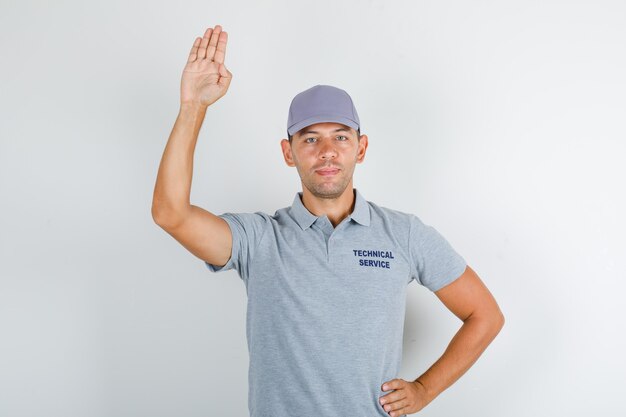 Technical service man holding palm up for greeting in grey t-shirt with cap and looking positive