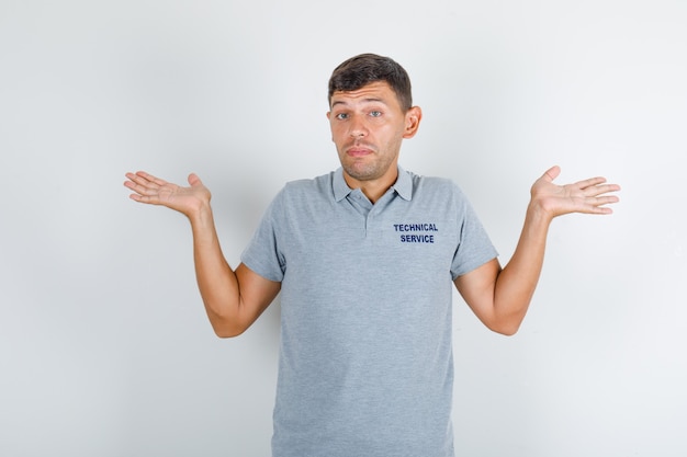 Free photo technical service man showing helpless gesture in grey t-shirt and looking confused