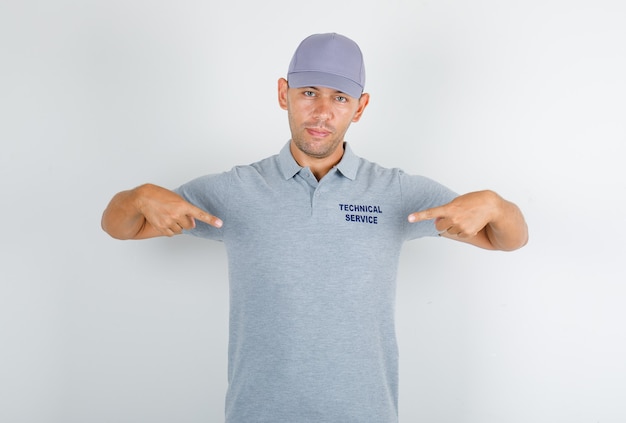 Free Photo technical service man showing himself in grey t-shirt with cap and looking confident