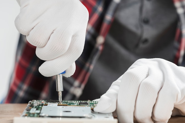 Free photo technician repairing computer motherboard with screwdriver