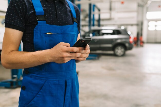 Technician using phone at car workshop