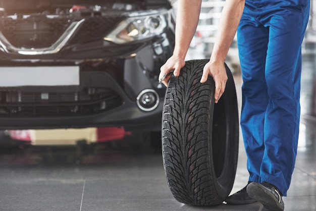 Free Photo technician with a blue workwear, holding a wrench and a tire while showing thumb up.