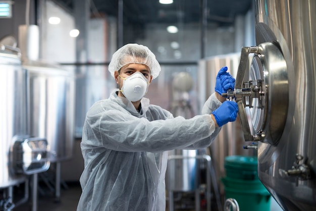 Technologist industrial worker opening processing tank in factory production line