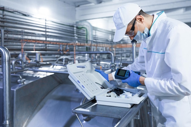 Technologist make set up of the special device while standing at the department of dairy factory