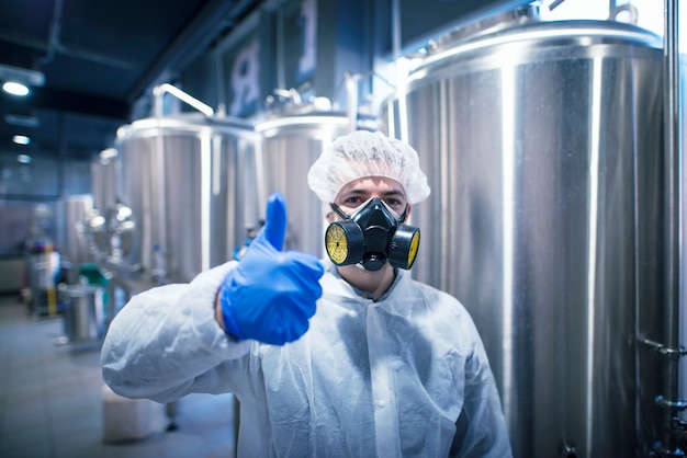 Technologist specialist in white protection suit wearing gas mask for safety at work