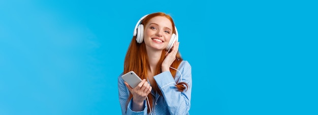 Technology music and entertainment concept cheerful attractive redhead caucasian woman listening mus