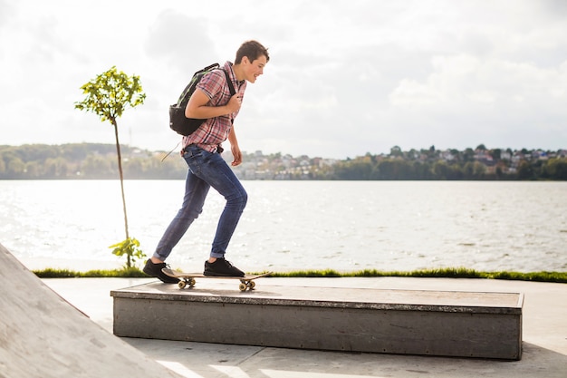 Teeenager skateboarding on border near water