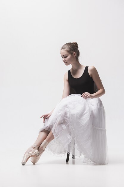 The teen ballerina in white pack sitting on chair