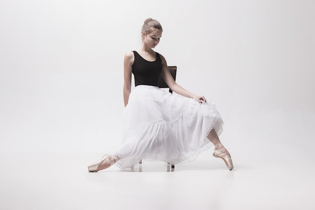 Teen ballerina in white skirt posing on the chair