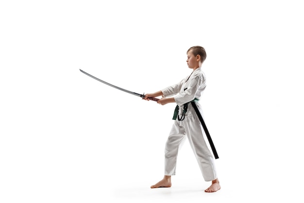 Teen boy fighting at Aikido training in martial arts school. Healthy lifestyle and sports concept. Fightrer in white kimono on white wall. Karate man with concentrated face in uniform.