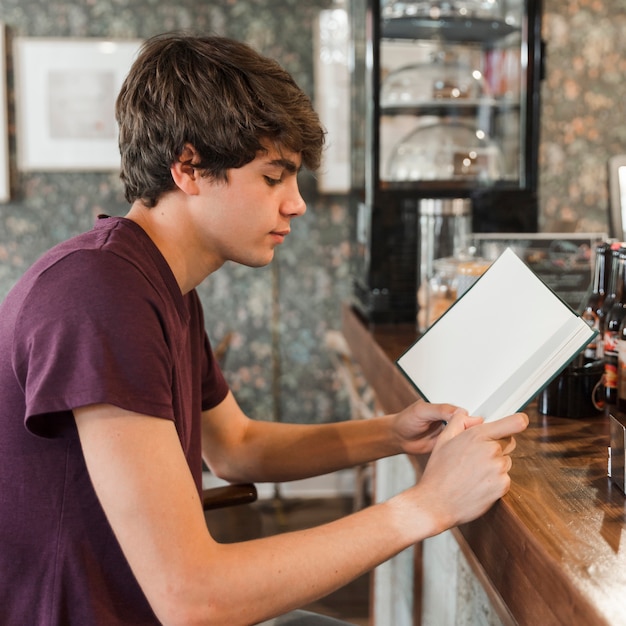 Free photo teen boy reading at cafe counter