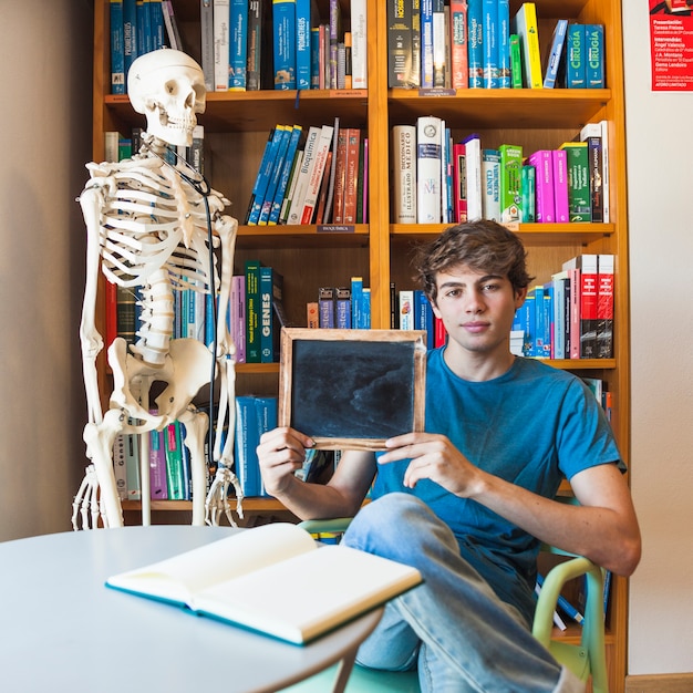 Free photo teen boy showing blackboard in library