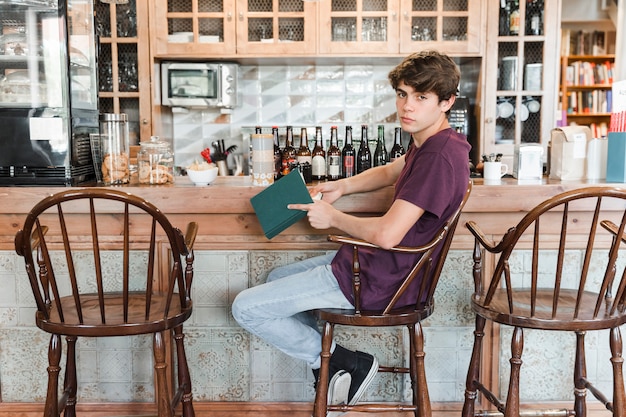 Teen boy with book near vintage counter in cafe