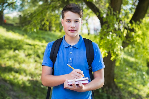 Free Photo teen boy writing in notebook