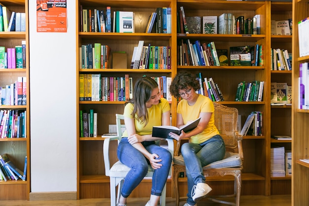 Teen friends reading book on chairs