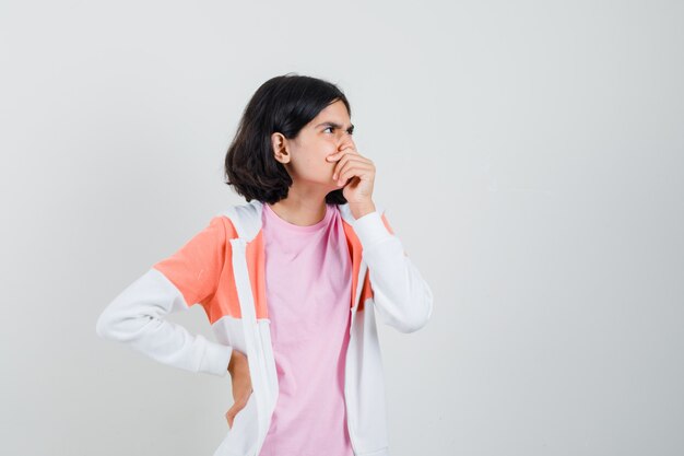 Teen girl analyzing something in jacket,pink shirt and looking pensive.