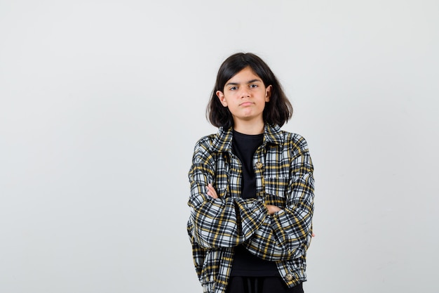 Teen girl holding arms folded in casual shirt and looking gloomy , front view.