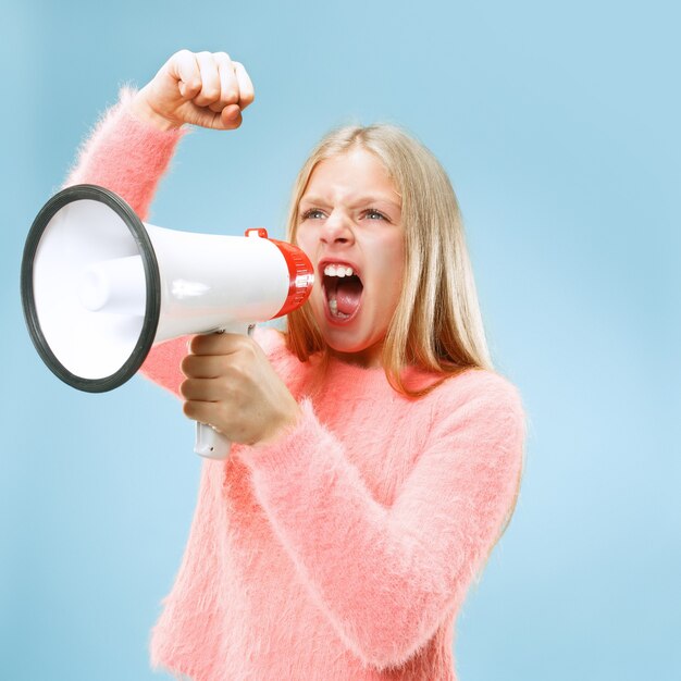 Teen girl making announcement with megaphone at blue studio