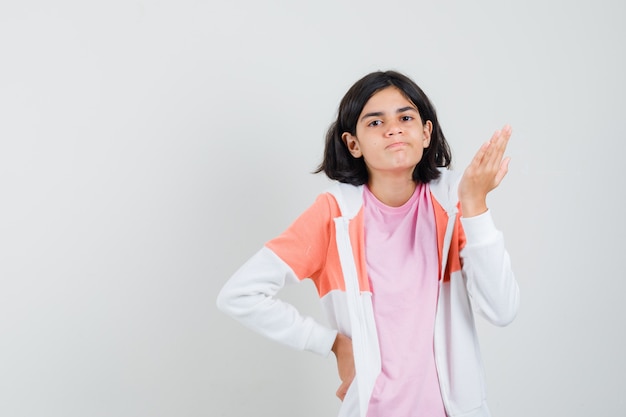 Free photo teen girl pointing aside with open palm in jacket, pink shirt and looking nervous