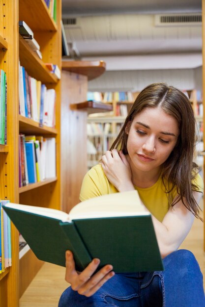 Teen girl scratching shoulder and reading book