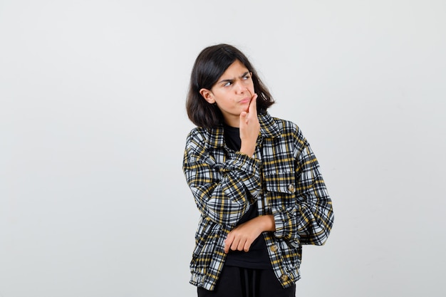 Teen girl suffering from toothache, looking aside in casual shirt and looking painful. front view.