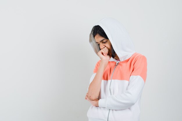 Teen girl in sweatshirt looking down and looking thoughtful.