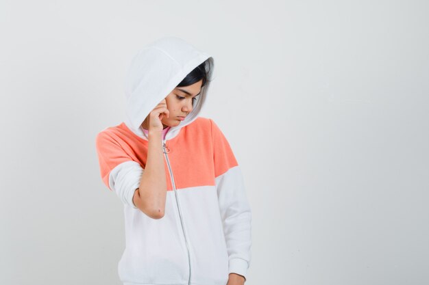 Teen girl in white jacket looking something at the floor and looking focused.