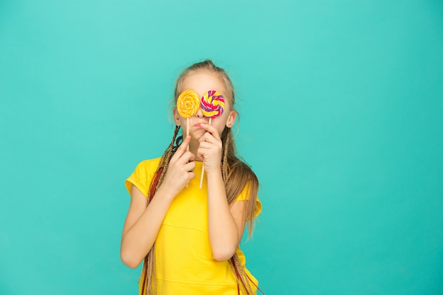 The teen girl with colorful lollipop on a blue wall