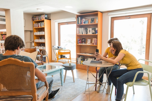 Free Photo teen girls taking picture of reading classmate