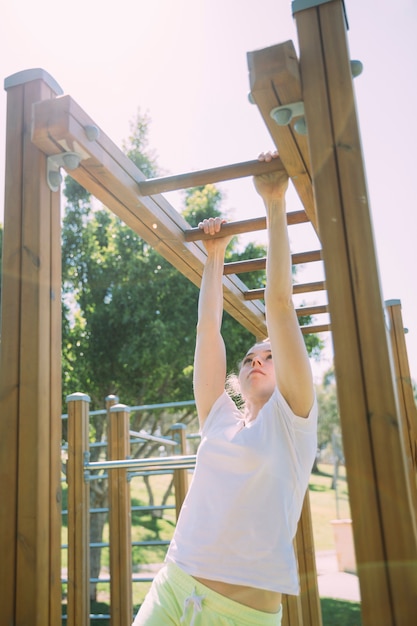 Teen schoolgirl climbing at jungle gym