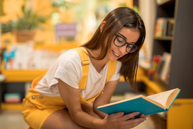 Teen schoolgirl crouching with book