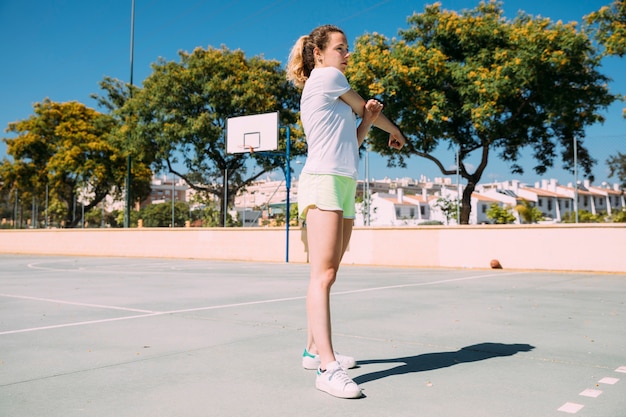 Teen schoolgirl stretching out arms at sportsground