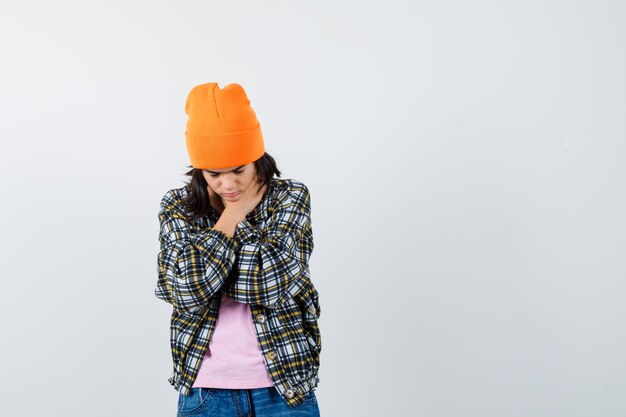 Teen woman in checkered shirt and beanie gesticulating isolated