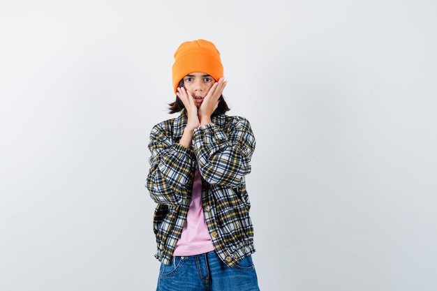 Teen woman in checkered shirt and beanie gesticulating isolated